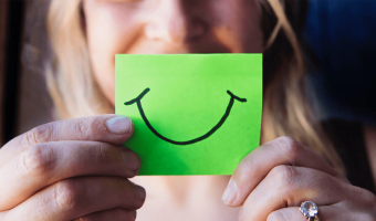 Image of a person holding a sticky note with a smiling face