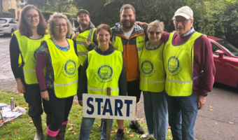 Photo shows 6 volunteer stewards in hi vis vests smiling at the camera