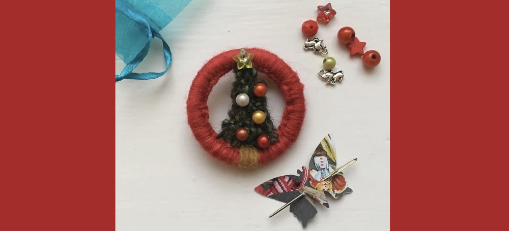 Photo shows a handmade Christmas Dorset button brooch in a red yarn ring with a Christmas tree centre.