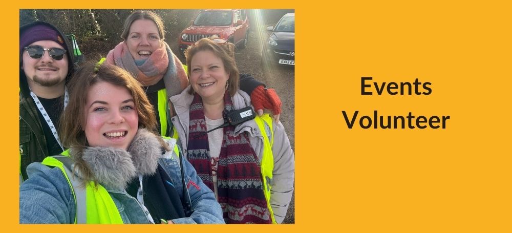 image shows four volunteers in hi vis vests outdoors at the drive in cinema, taking a selfie to the camera in a car park